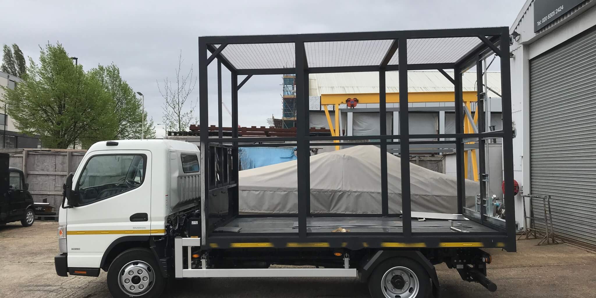 White lorry with large cage on the back for household rubbish