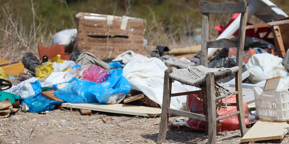shutterstock_216513955 Dumped broken chair surrounded by rubbish on wasteland