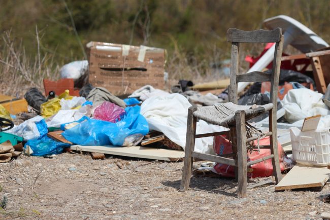 shutterstock_216513955 Dumped broken chair surrounded by rubbish on wasteland
