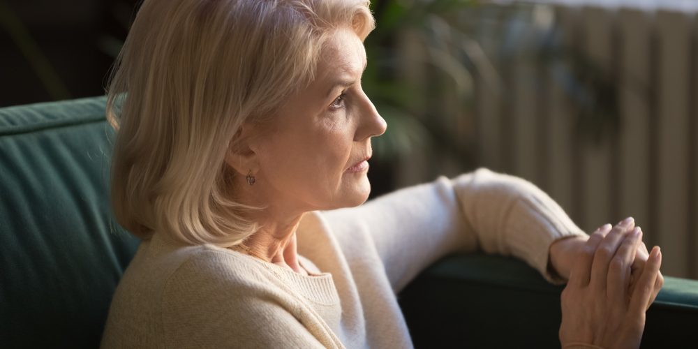 Pensive,Mature,Woman,Sit,On,Couch,Look,In,Distance,Thinking Woman looking sad