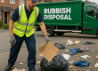 Rubbish Disposal team loading varied waste including furniture, garden cuttings, cardboard boxes and plastic bags into a branded white van on a clean residential Essex street.