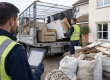 Professional rubbish clearance team using digital waste tracking while loading renovation waste into a caged lorry